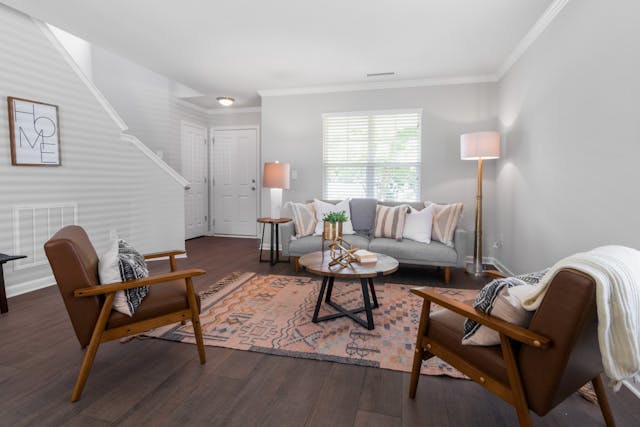 a white living room with wood flooring a brown leather armchairs