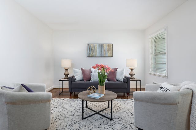 a white living room with a dark grey couch and light grey chairs