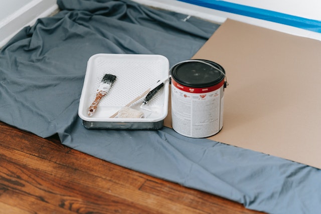 blue tarp with paint tray, can and rollers the prep for wall painting