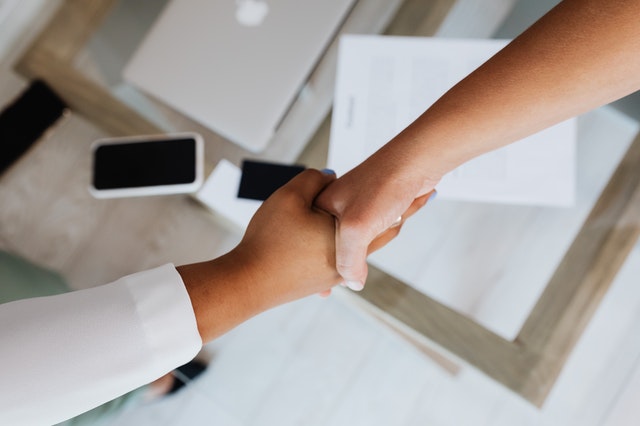 Two people shaking hands across a desk