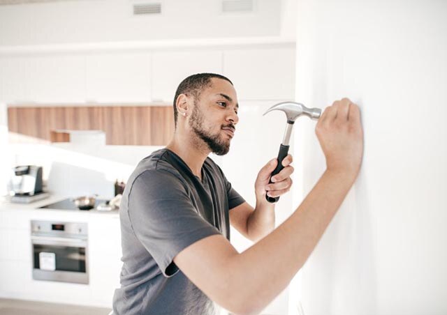 person hammering nail into wall